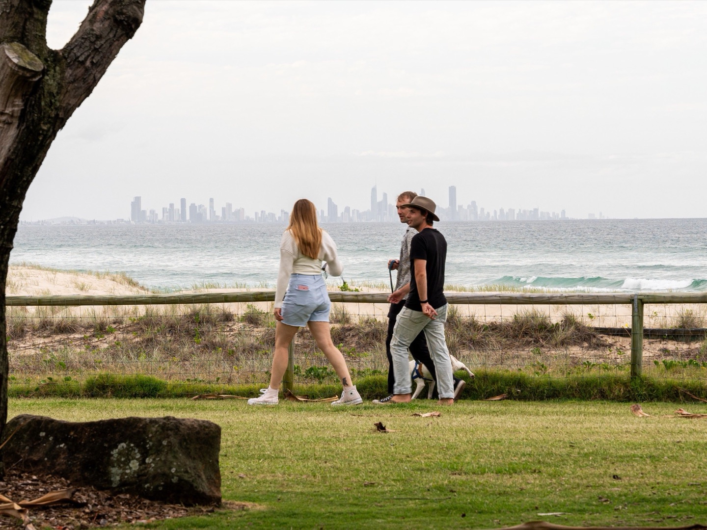 Three friends walking along a beachfront path with a distant skyline